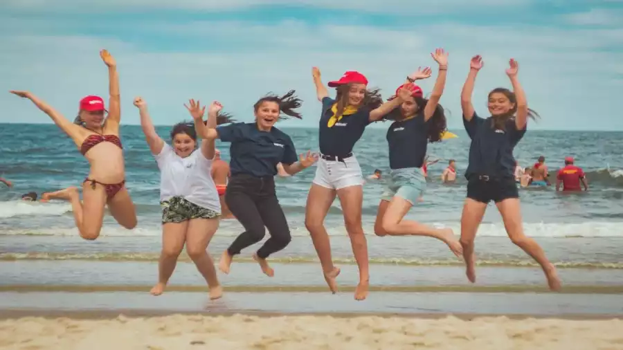 uczestnicy obozu letniego skaczą na plaży