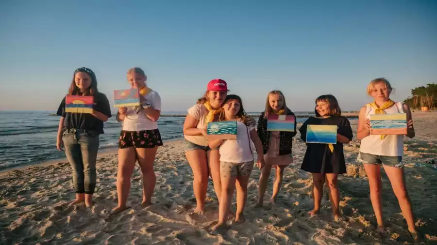uczestniczki kolonii plastycznej prezentują swoje prace na plaży