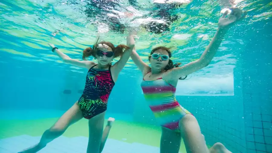 uczestniczki kolonii letniej nurkują w basenie